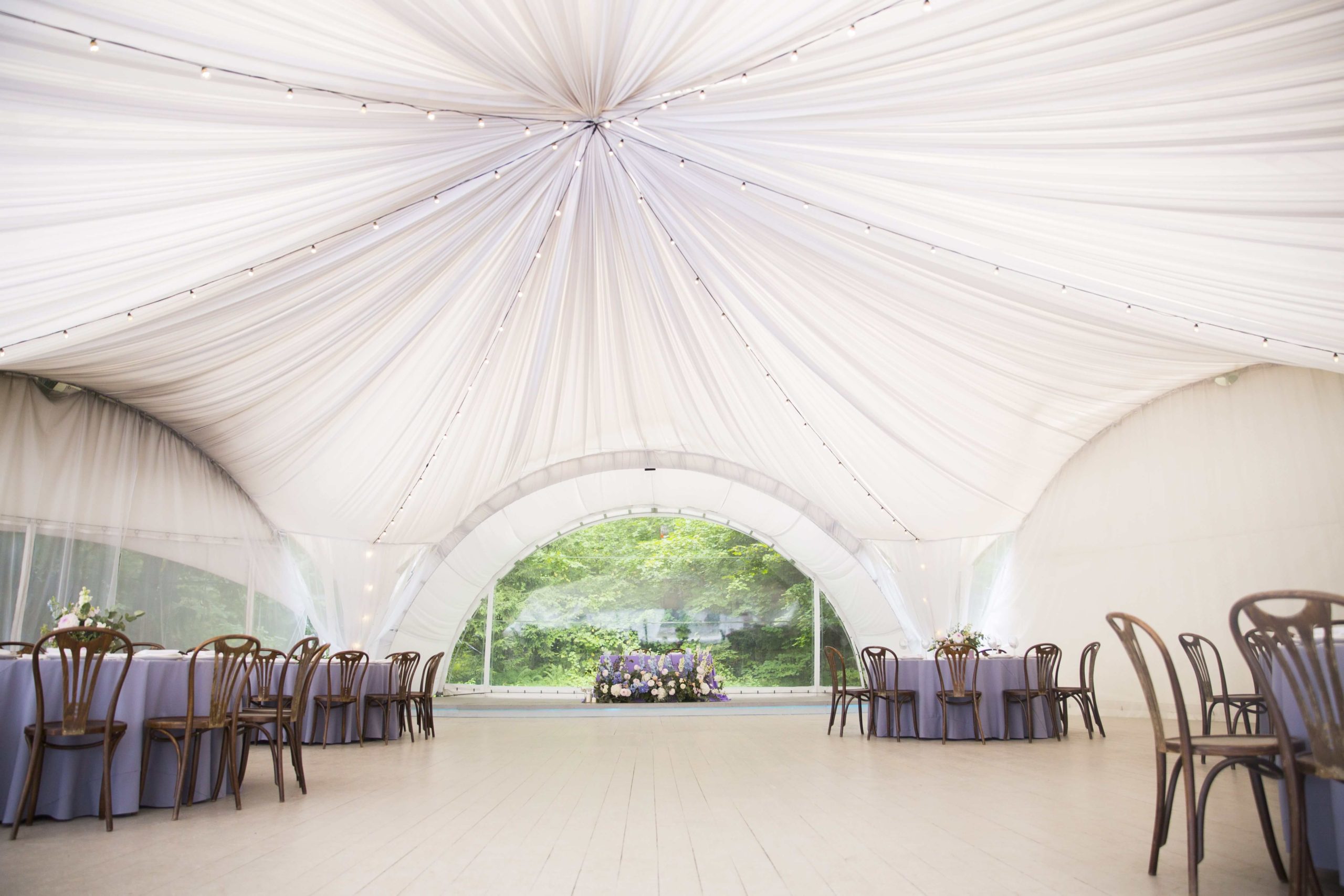 big white wedding tent with beautiful decorations tables with floral decorations wooden chairs min 2 scaled